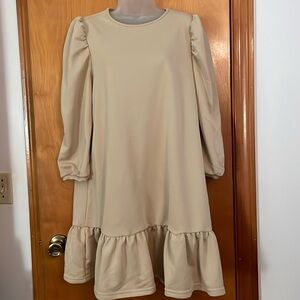 Beige dress with large ruffle bottom and small gathering at top of sleeves